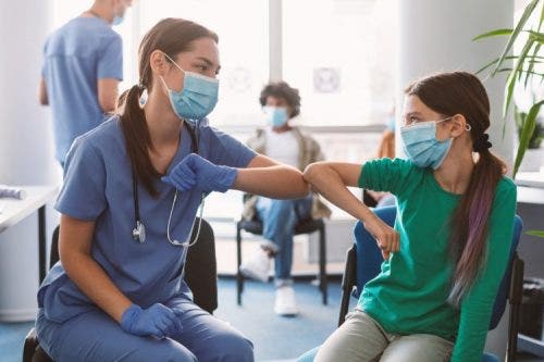 A clinician bumps elbows with a young patient.