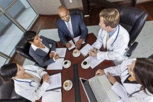 Healthcare workers and administrators having a meeting while looking at a laptop in a conference room.
