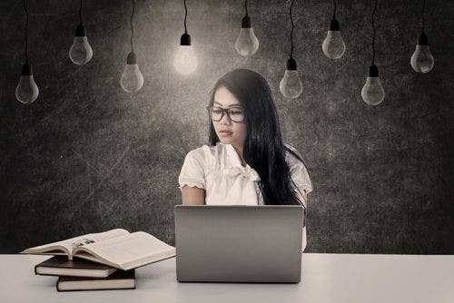 Young female student study with her laptop under light bulbs