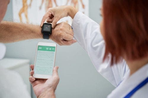 A doctor helps a patient program a wearable device.