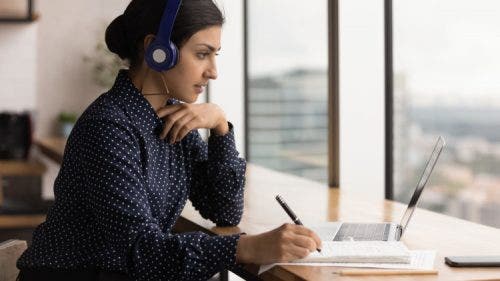 A Healthcare MBA student takes notes during an online class.