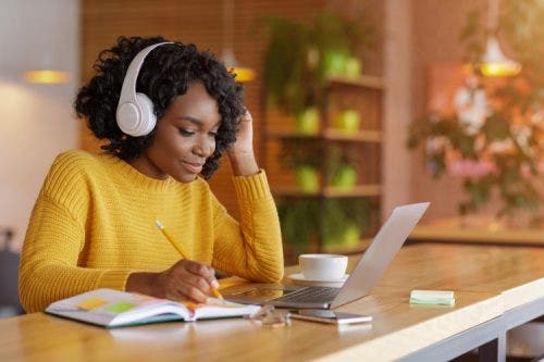 An MBA student takes notes during an online class.
