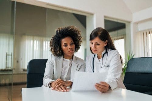 A healthcare administrator and a doctor read a document.