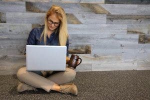 Healthcare MBA student on computer with cup in hand.